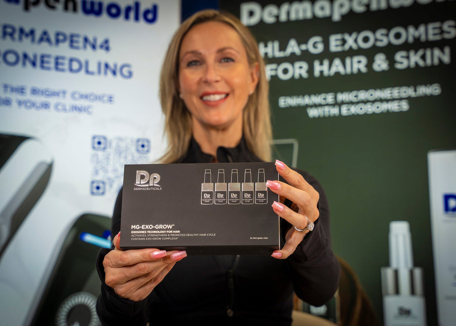 Woman holding a box labeled 'DP Dermapen' at an event with promotional banners in the background.