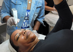 Load image into Gallery viewer, Person receiving a facial treatment with a professional in a clinical setting.