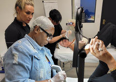 Load image into Gallery viewer, Person receiving a facial treatment in a clinical setting with another person assisting.